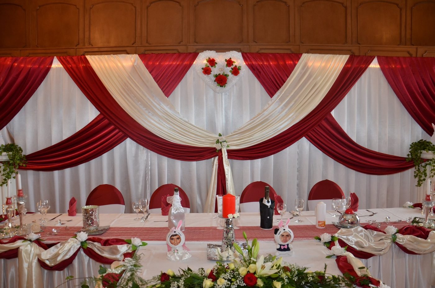 Brauttisch vor Backdrop mit Drapierungen in Bordeaux und Weiß und Rosenherz