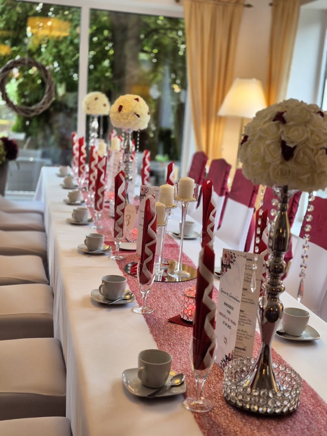 Lange Festtafel mit Rosenkugeln auf Ständern und Bordeaux-Akzenten