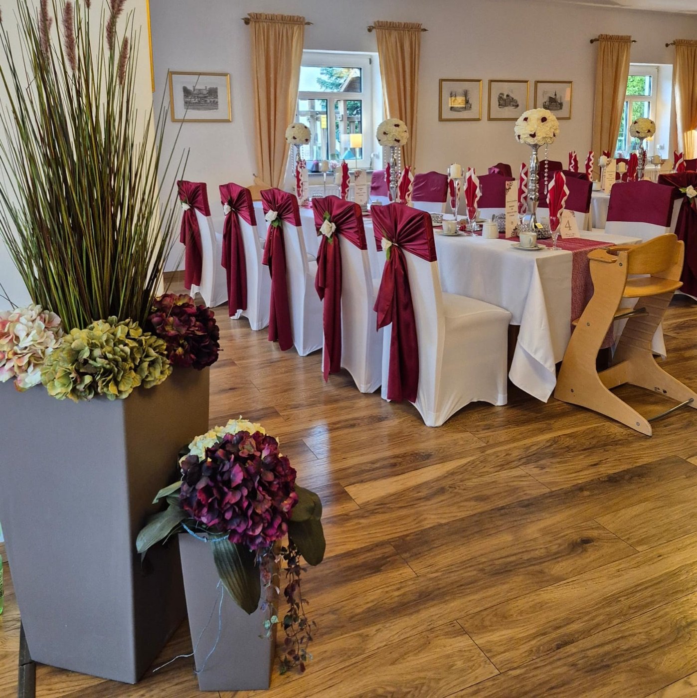 Festsaal mit Bordeaux-Stuhlschleifen und Hortensien in Bodenvasen