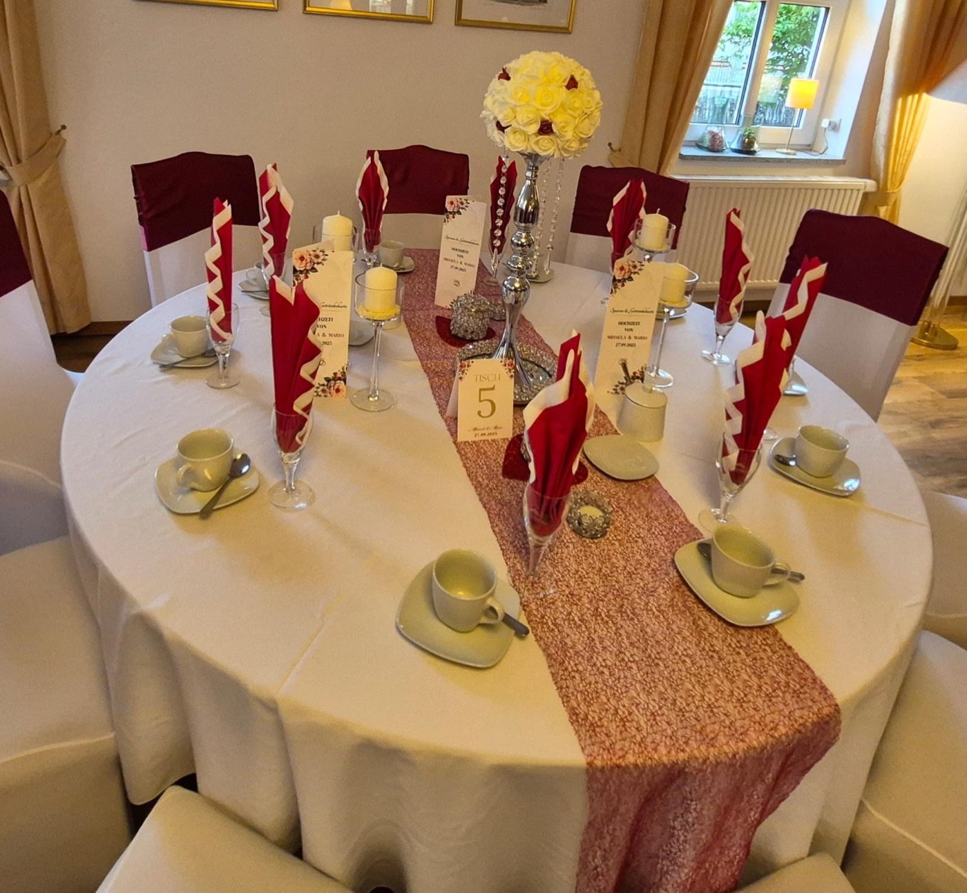 Runder Tisch mit hoher Rosenkugel und Bordeaux-Servietten