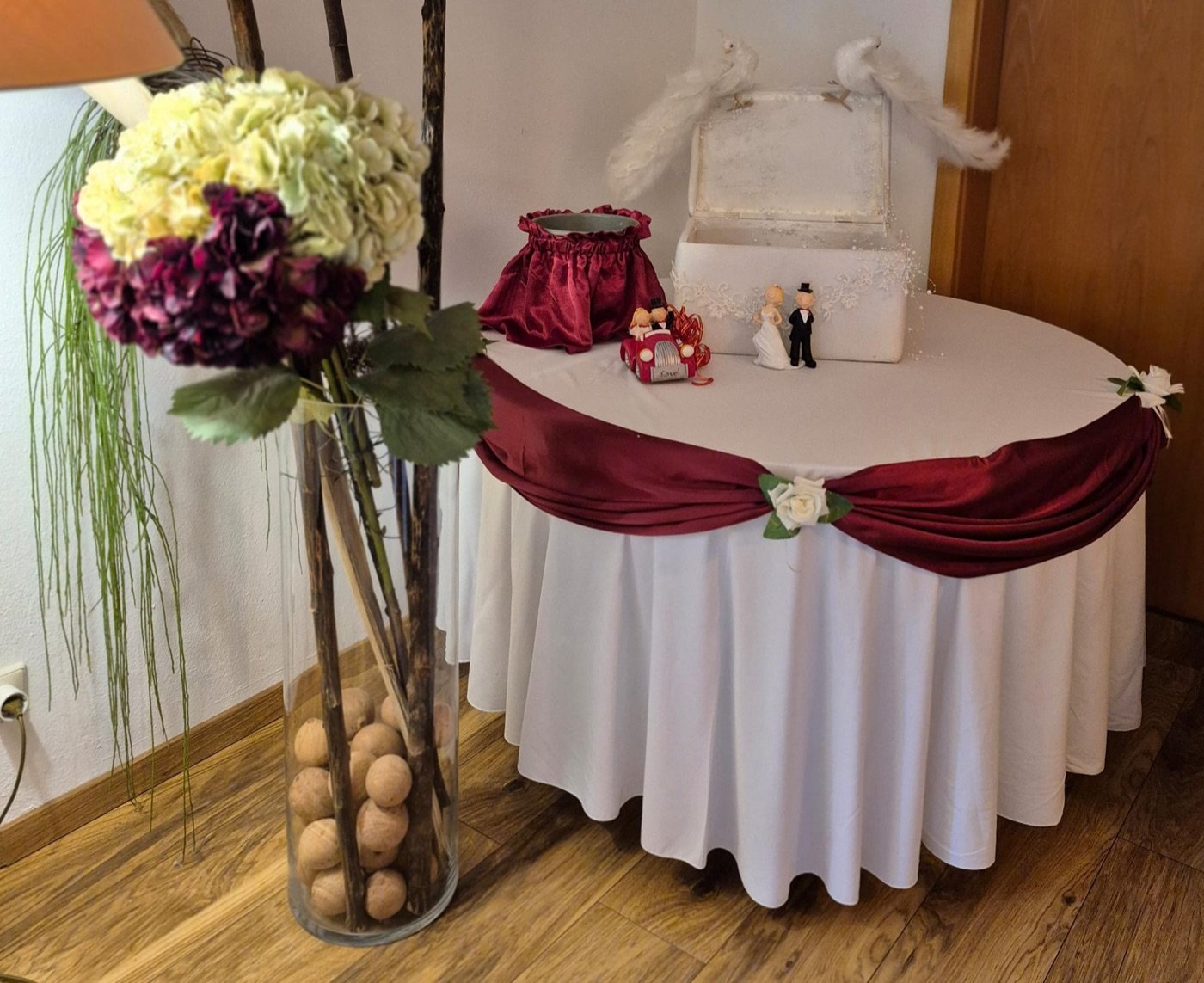 Geschenktisch mit Bordeaux-Drapierung und Hortensiengesteck