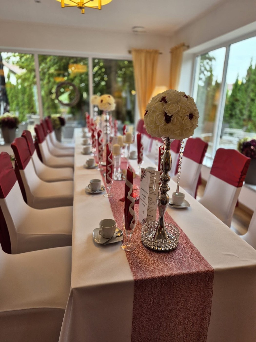 Lange Tafel mit rosé Läufer, Bordeaux-Stühlen und Rosenkugeln
