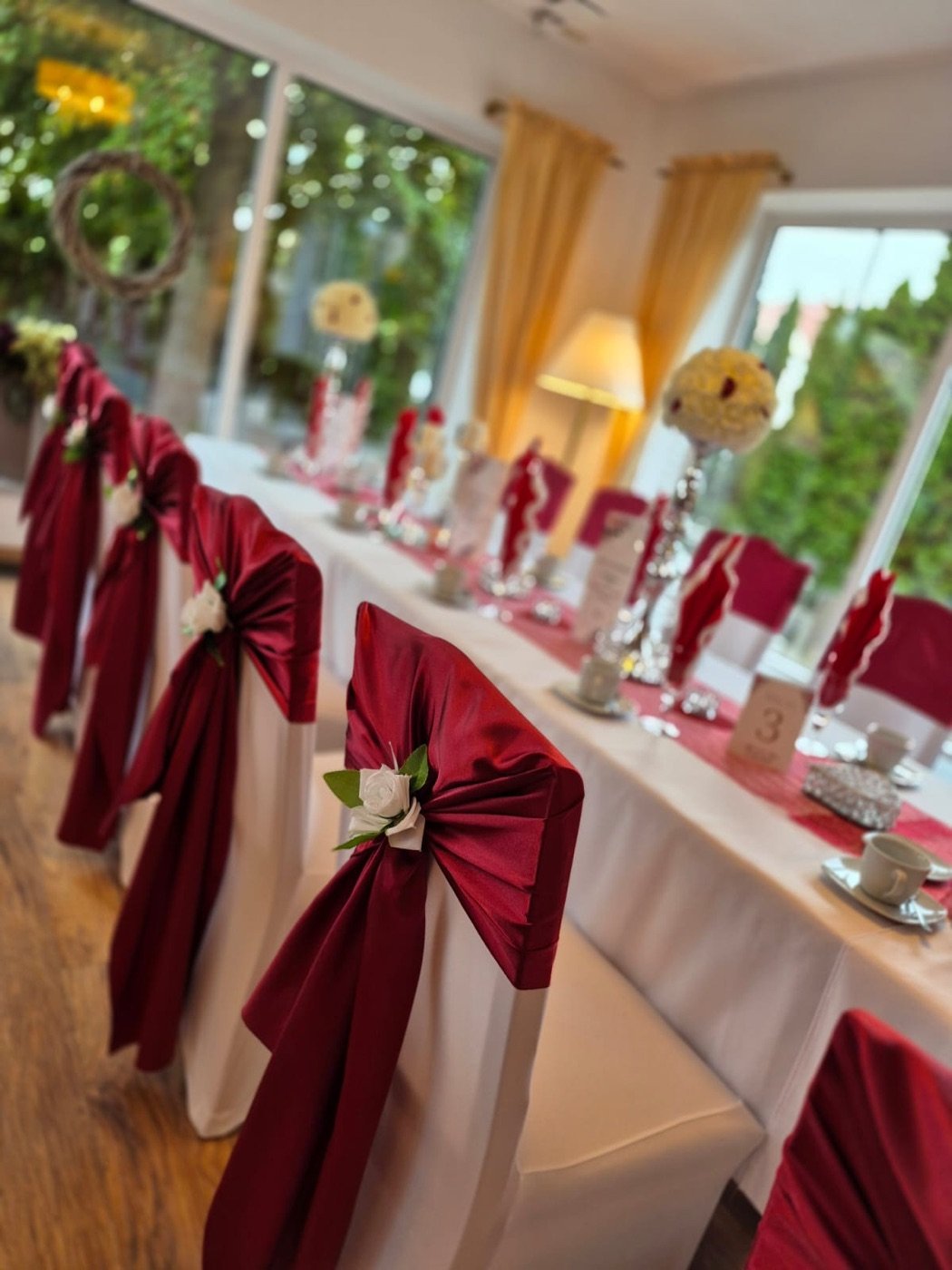 Stuhlreihe mit Bordeaux-Satin-Schleifen an der Festtafel