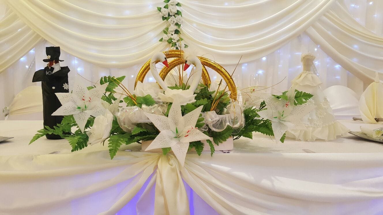 Blumengesteck mit Lilien und goldenen Ringen auf dem Brauttisch