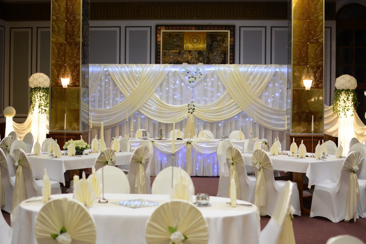 Eleganter Ballsaal mit runden Tischen und Hochzeitsdeko in Creme