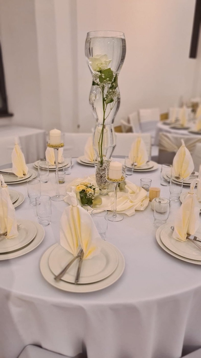 Runder Tisch mit hoher Vase, weißer Rose und Servietten in Creme
