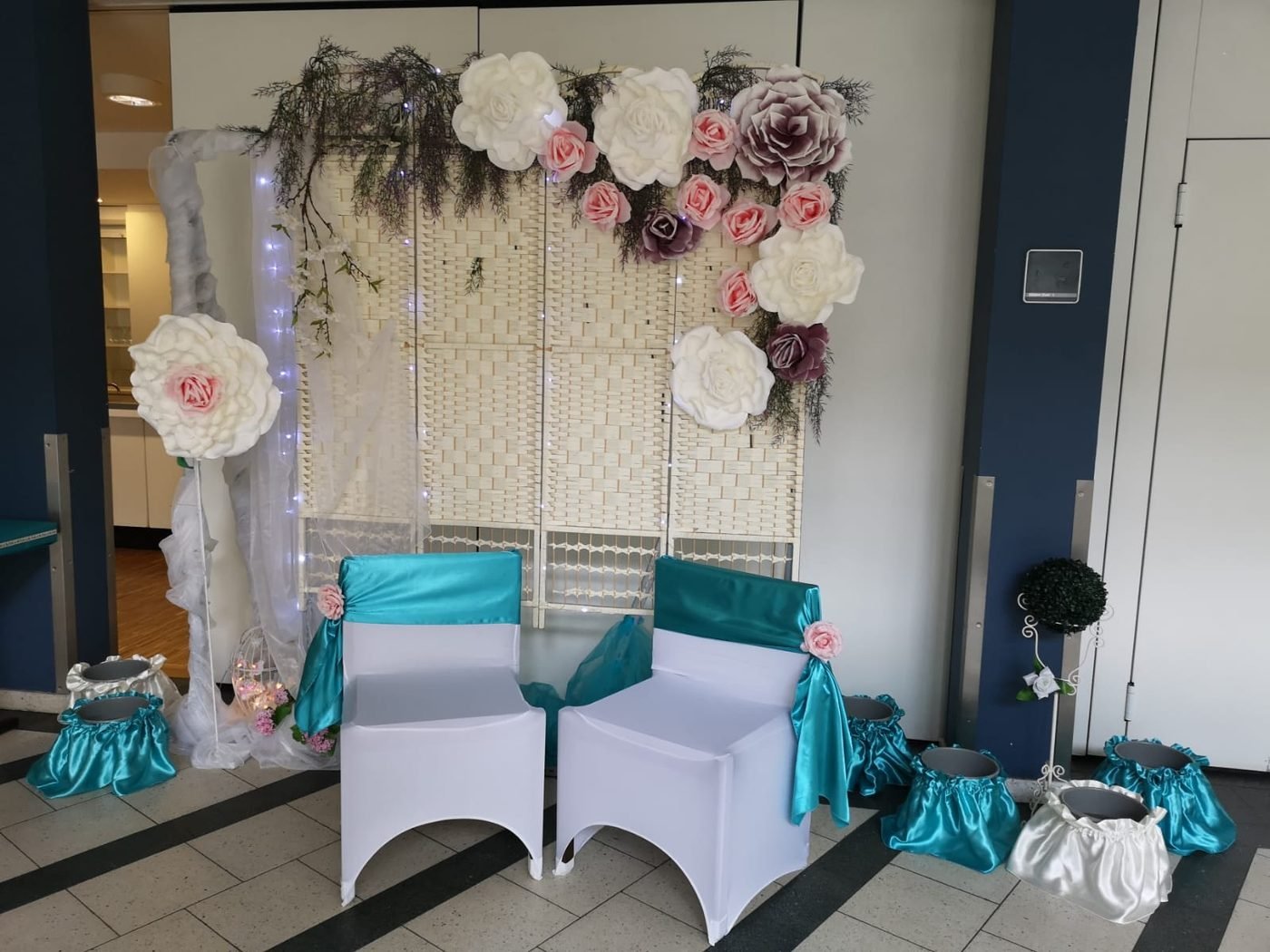 Fotoecke mit Papierblumen-Wand und Sesseln für Hochzeitsfotos