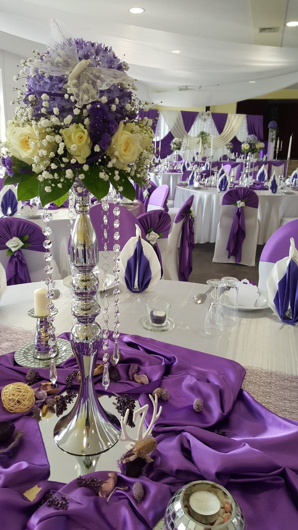 Festsaal in Lila mit hohen Blumenständern und Satin-Läufern