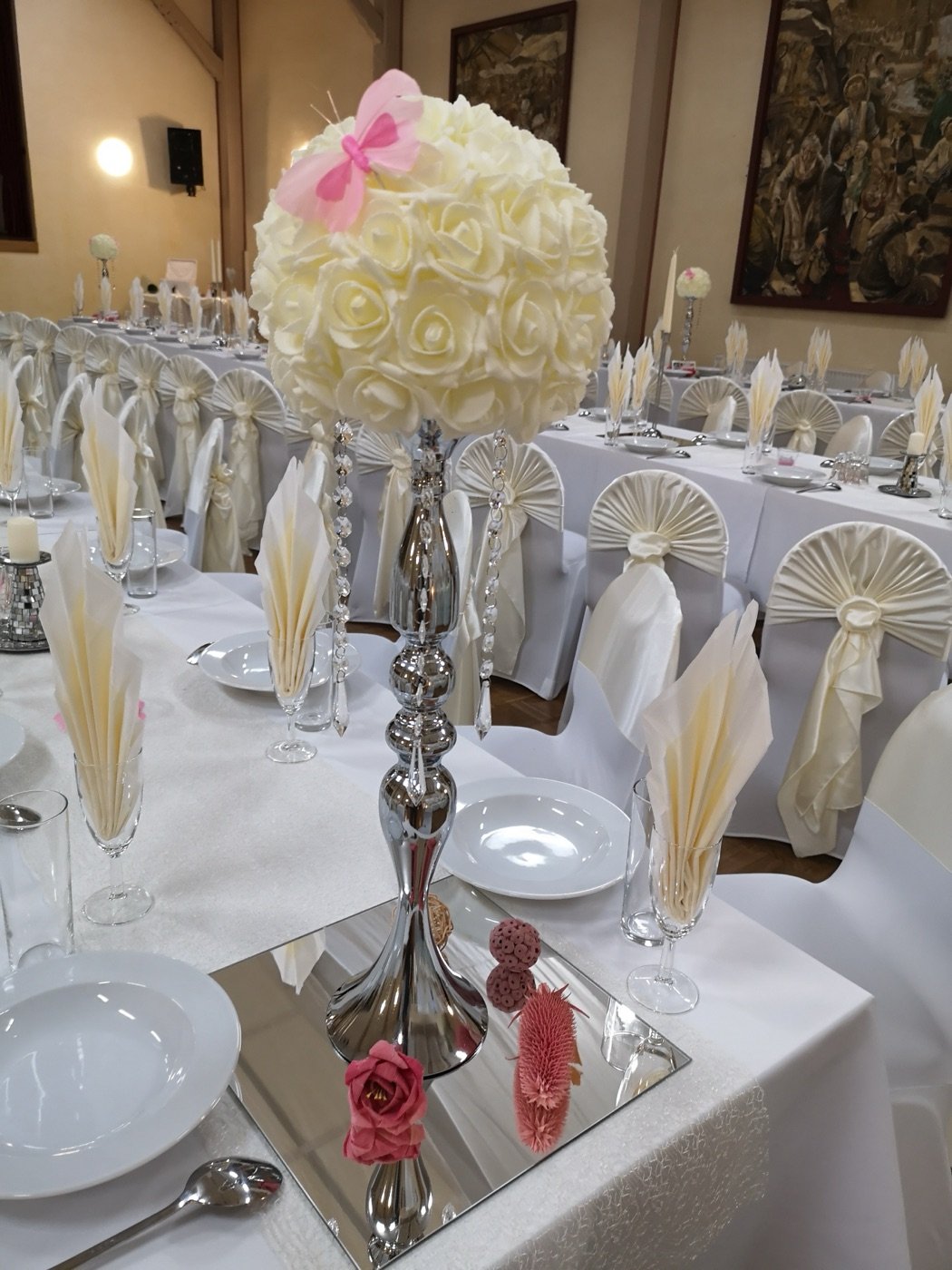 Weiße Rosenkugel auf silbernem Ständer an der langen Festtafel